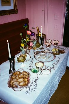 a table topped with plates filled with food and flowers next to a wall mounted clock