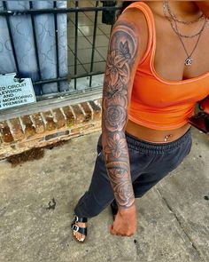 a woman sitting on the ground with tattoos on her arm