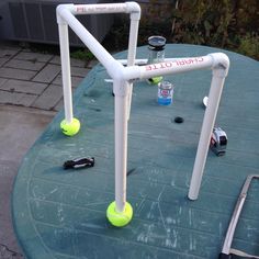 tennis balls are sitting on the edge of an outdoor table with white pipes and plastic cups