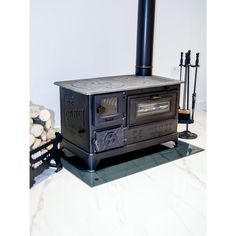 an old fashioned stove sitting on top of a counter next to logs and a chair