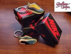 three nike shoes are sitting on top of a box with a keychain in it