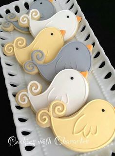 decorated cookies in the shape of birds on a white platter with black polka dots