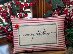 a red and white pillow sitting on top of a wooden table next to a plant