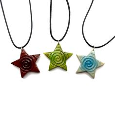 three star shaped necklaces with spiral designs on them, one is green and the other is red