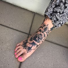 a woman's foot with a rose tattoo on it