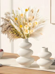 three white vases with flowers in them on a table