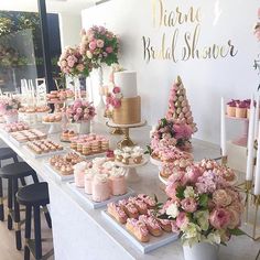 a table with pink flowers and cupcakes on it