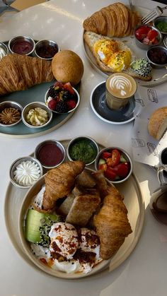 two plates with croissants and other food on them