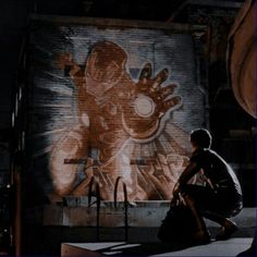 a man sitting on top of a wooden table in front of a wall with graffiti