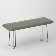 a long bench with metal legs and a green upholstered cushion on the top