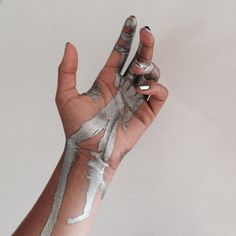 a hand with white paint on it holding an object in the air