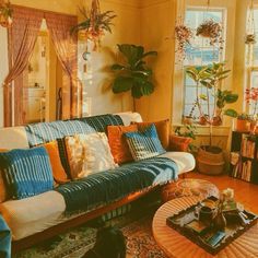 a living room filled with lots of furniture and plants on top of the couches