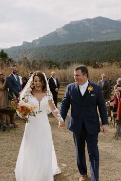 a bride and groom walking down the aisle after their wedding ceremony in front of an outdoor crowd