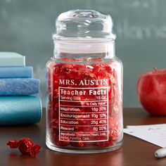 a glass jar filled with red candy sitting on top of a table next to books