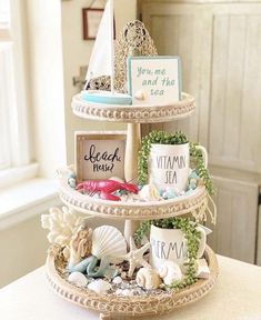 a three tiered tray with seashells and signs on it