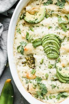 a white casserole dish filled with shrimp, cheese and avocado garnish