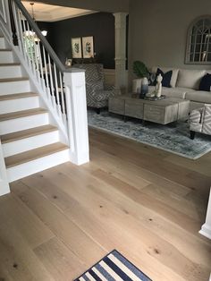 a living room filled with furniture and a stair case next to a white banister