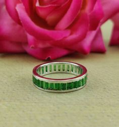 a close up of a ring with a rose in the background