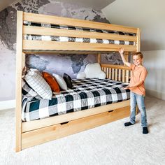 a young boy standing next to a wooden bunk bed