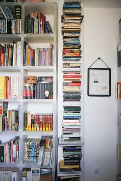 a bookshelf filled with lots of books next to a wall full of books