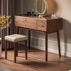 a dressing table with a mirror and stool next to a plant in a vase on the floor