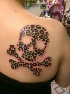 a skull and crossbone tattoo on the back of a woman's shoulder