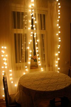 a dining room table with lights on the curtains