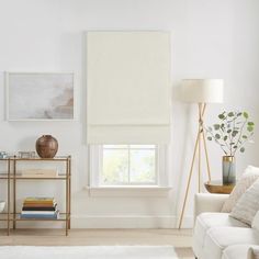 a living room filled with furniture and a large window covered in white roman blind shades