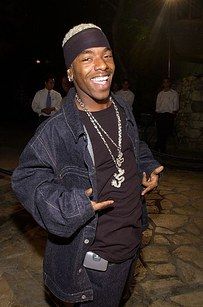 a man standing in front of a stone wall at night with his arms crossed and smiling