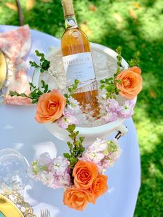 a bottle of wine sitting on top of a table next to some flowers and plates