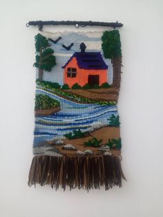 an embroidered wall hanging with a house on it