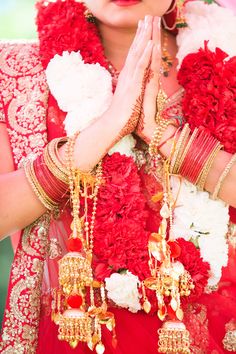 a woman dressed in red and gold holding her hands to her chest with flowers on it