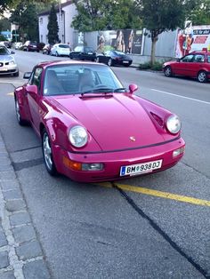 a pink sports car is parked on the side of the road