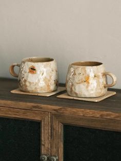 two coffee mugs sitting on top of a wooden table