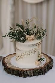 a white wedding cake sitting on top of a wooden slice next to a knife and fork