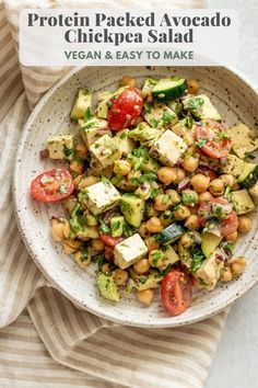 a white bowl filled with chickpea salad on top of a striped cloth next to a fork