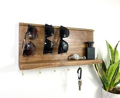 a wooden shelf with sunglasses and keys hanging from it's hooks on the wall