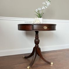 a wooden table with flowers on it and a white flower in a vase sitting on top