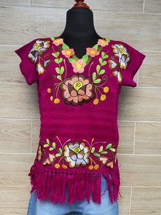 This Mexican blouse is made of pedal loom and embroidered by artisans from Oaxaca, Mx. This blouse comes in one size and fits S / M Blouse embroidered in a craft machine Mexican textile art has centuries of history and creativity throughout the country. Mexico is recognized as one of the leading countries with a beautiful aristic production in the textile world, miraculous hands of talented artisans from different states of the country create stunning embroidery clothing, and various items. #Oax Embroidered Bohemian Purple Blouse, Bohemian Embroidered Purple Blouse, Purple Embroidered Bohemian Blouse, Festive Bohemian Tops With Woven Motifs, Bohemian Purple Embroidered Blouse, Bohemian Tops With Woven Motifs For Festive Occasions, Pink Top With Intricate Embroidery For Festivals, Traditional Spring Tops With Woven Motifs, Folk Style Short Sleeve Tops With Woven Motifs