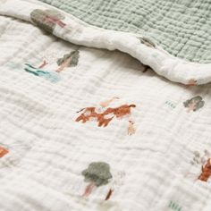 an unmade baby blanket with animals and trees printed on it's coverlet