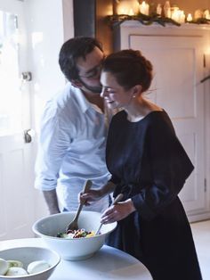 a man and woman standing in front of a bowl of food