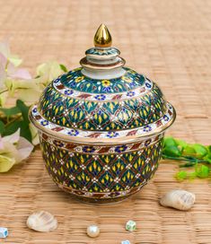 a decorative bowl sitting on top of a table next to flowers and seashells