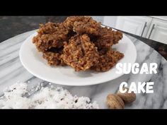 a white plate topped with cookies on top of a marble counter next to a pile of coconut