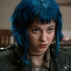 a woman with blue hair wearing a leather jacket