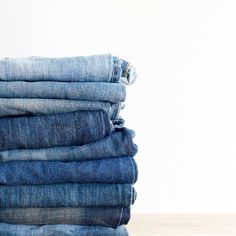 a stack of blue jeans sitting on top of a wooden table