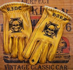 pair of yellow leather gloves with skull and crossbones on them, against wooden background