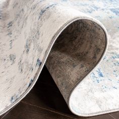 a white and blue rug on top of a wooden floor