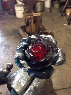 a red rose sitting on top of a metal object in a room filled with other items