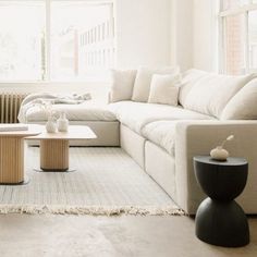 a living room filled with white furniture and large windows in the back drop off wall