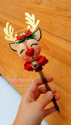 a hand holding a pen with a reindeer head on it